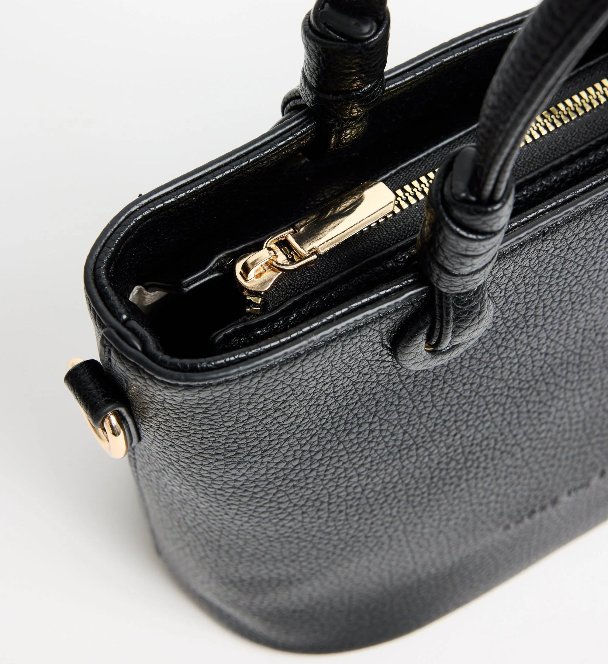 Close-up of a black handbag with gold zipper on a white background