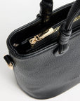 Close-up of a black handbag with gold zipper on a white background