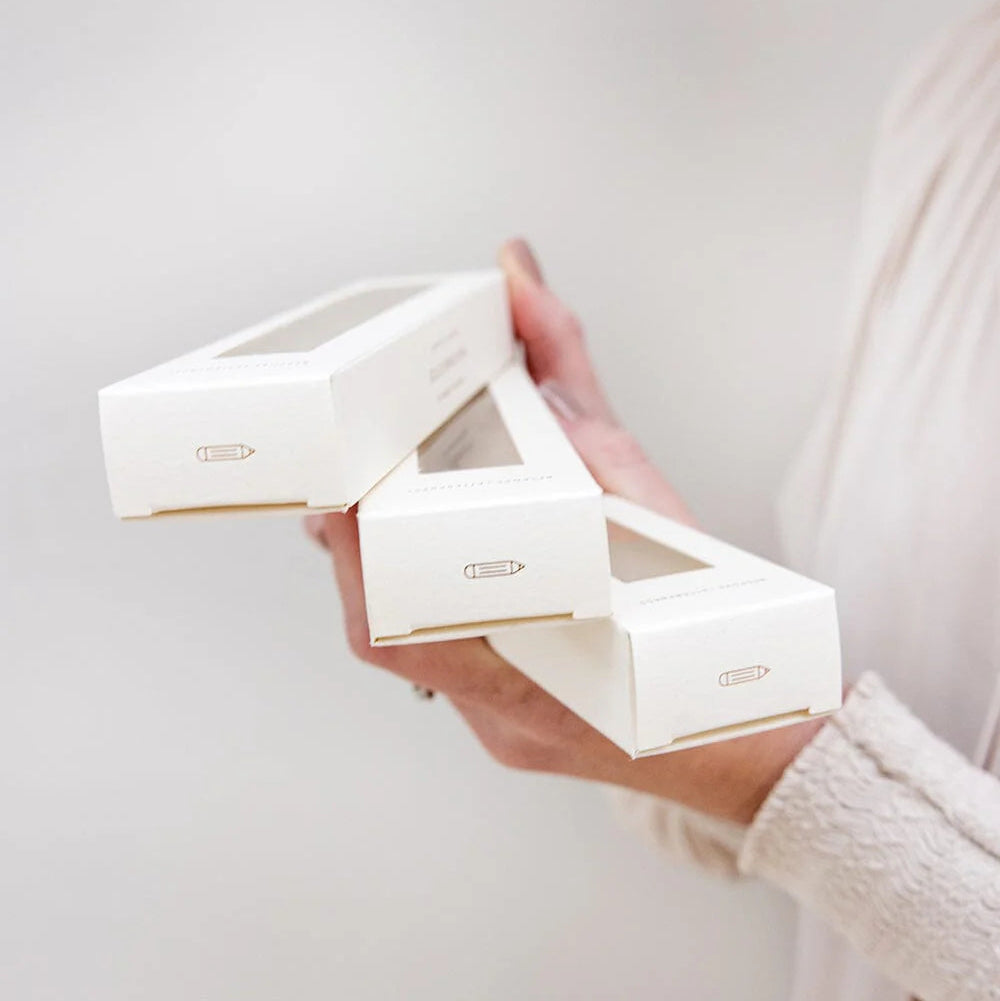 Person holding a set of white jewelry boxes with a plain background