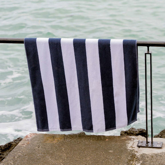 Navy and white striped towel hanging on a railing by the water.