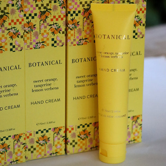 Yellow tube of Botanical hand cream with floral packaging in the background