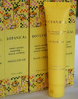 Yellow tube of Botanical hand cream with floral packaging in the background