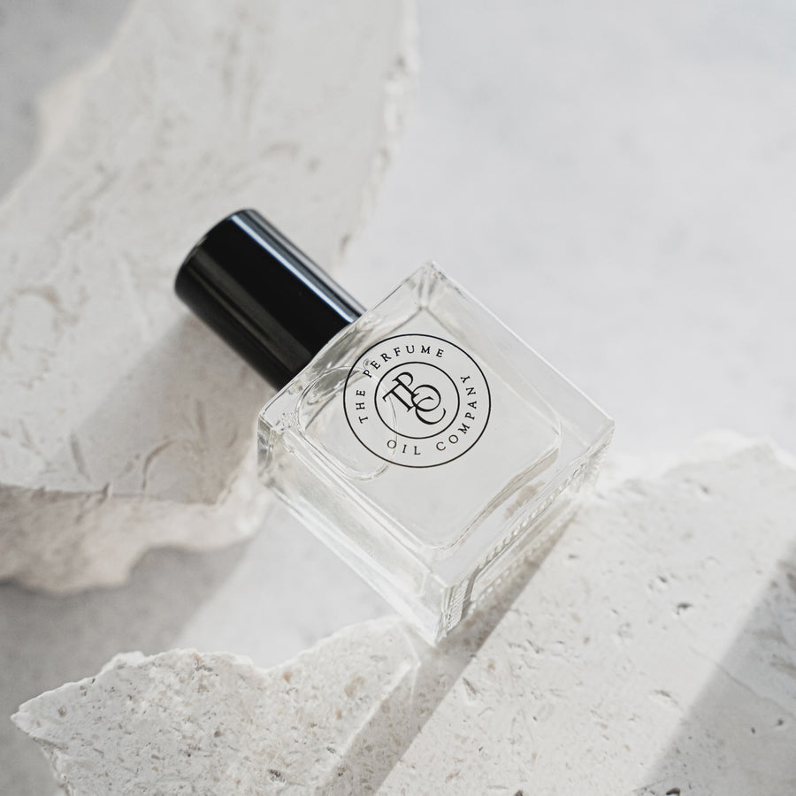 Perfume bottle with black cap on a textured white surface