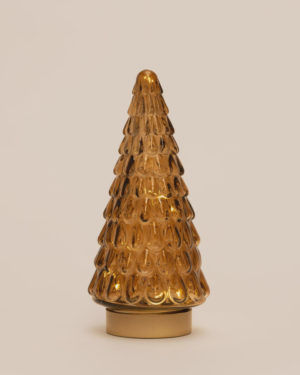A small amber glass Christmas tree ornament with a textured, scalloped pattern and a gold-colored circular base, set against a solid light beige background.