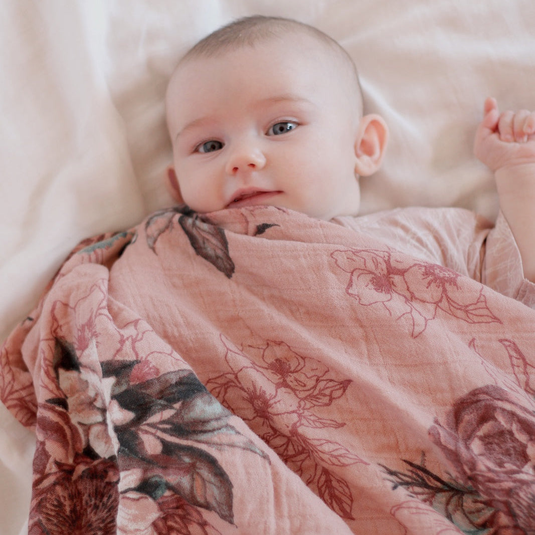 Baby wrapped in a floral blanket on a soft surface