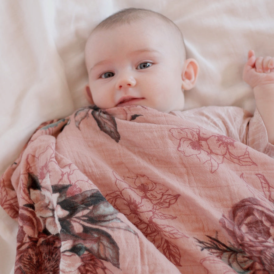Baby wrapped in a floral blanket on a soft surface