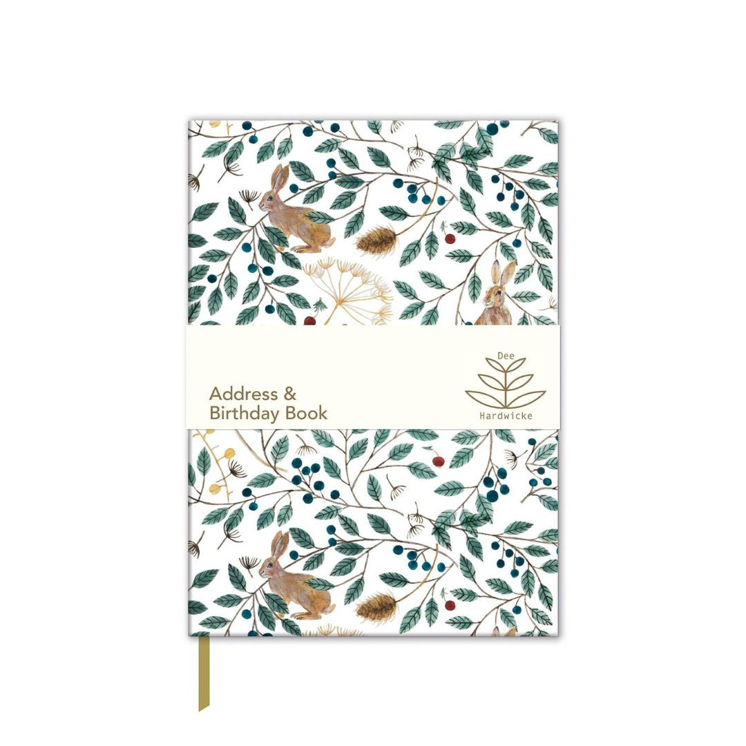 A hardcover address and birthday book with a white cover decorated with a botanical and woodland pattern of rabbits, leaves, berries, and pinecones. A cream-colored paper band wraps around the middle, featuring the text 'Address &amp; Birthday Book' and the brand name 'Kerricliffe'.