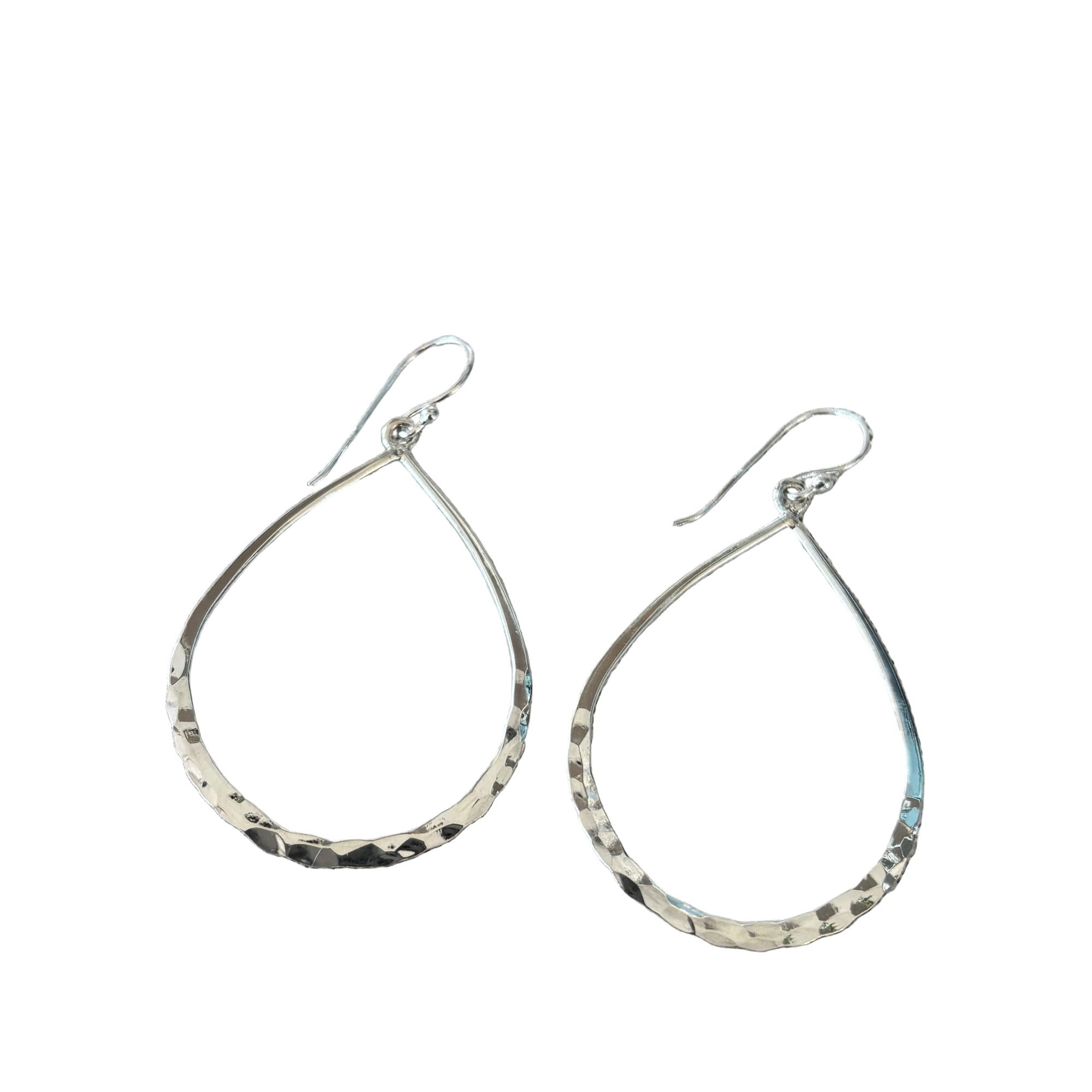 Teardrop-shaped silver earrings on a textured surface