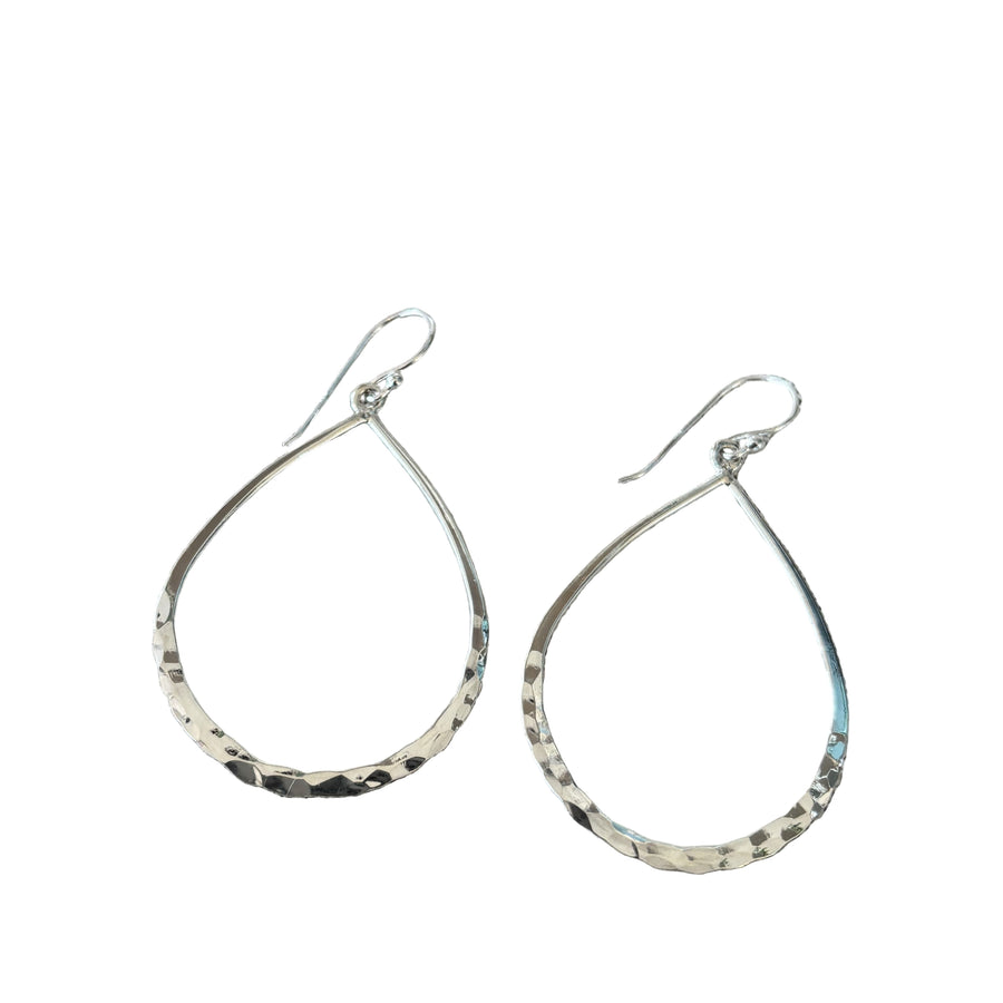 Teardrop-shaped silver earrings on a textured surface