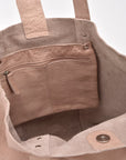 Close-up of a brown leather bag with visible stitching and brand name.