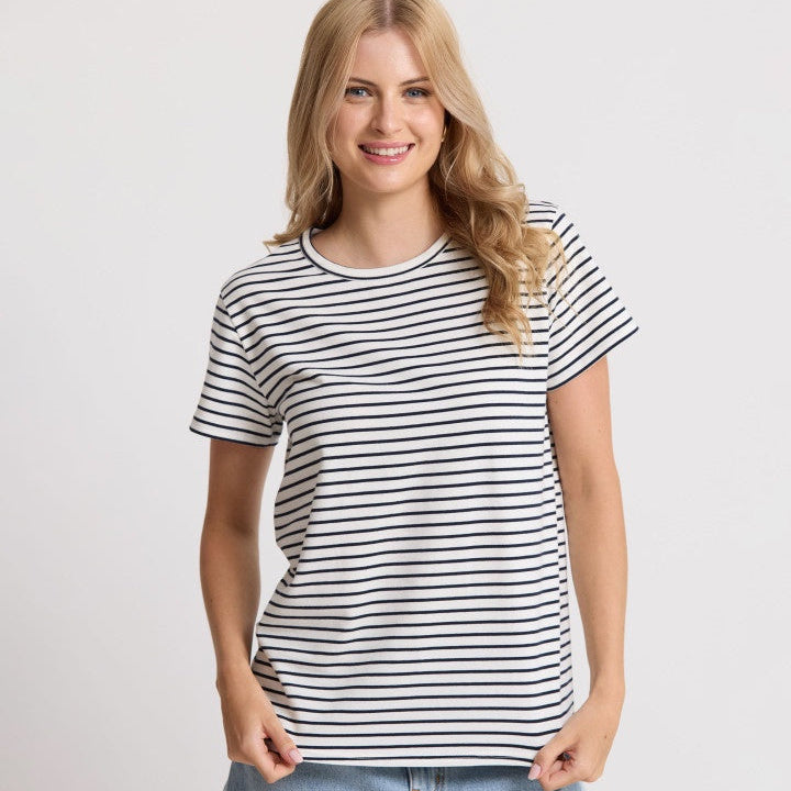 Woman wearing a black and white striped t-shirt and blue jeans on a light gray background