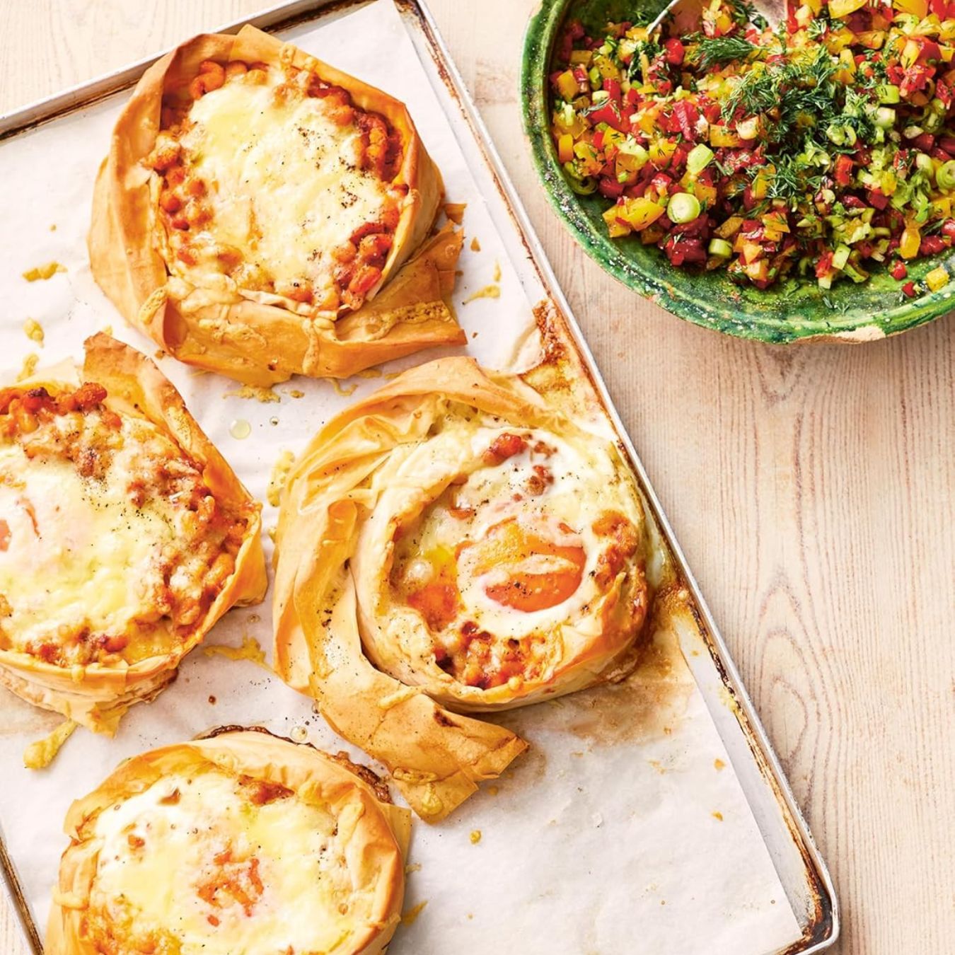 Puff pastry tarts on a baking tray with a side of salad on a wooden surface