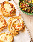 Puff pastry tarts on a baking tray with a side of salad on a wooden surface