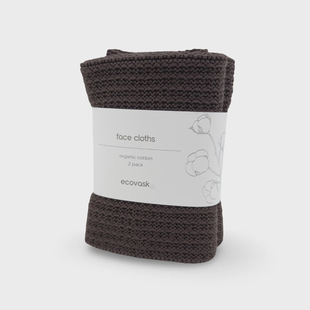 A folded pack of two dark brown knitted face cloths wrapped in a white paper band labeled 'face cloths organic cotton 2 pack ecovask' on a light gray background.