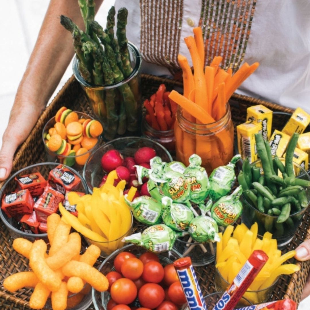 Assorted snacks including candy, vegetables, and chips on a tray.