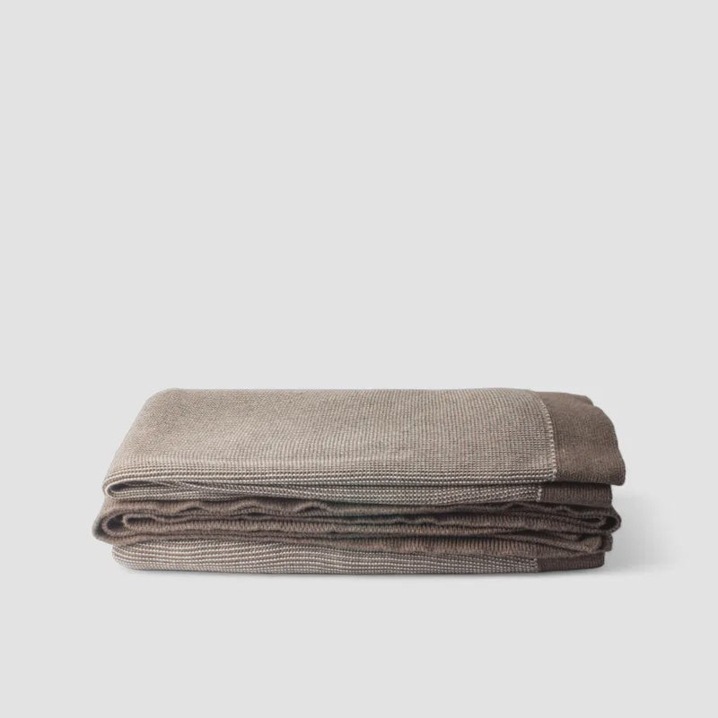 Folded brown blanket on a light gray background