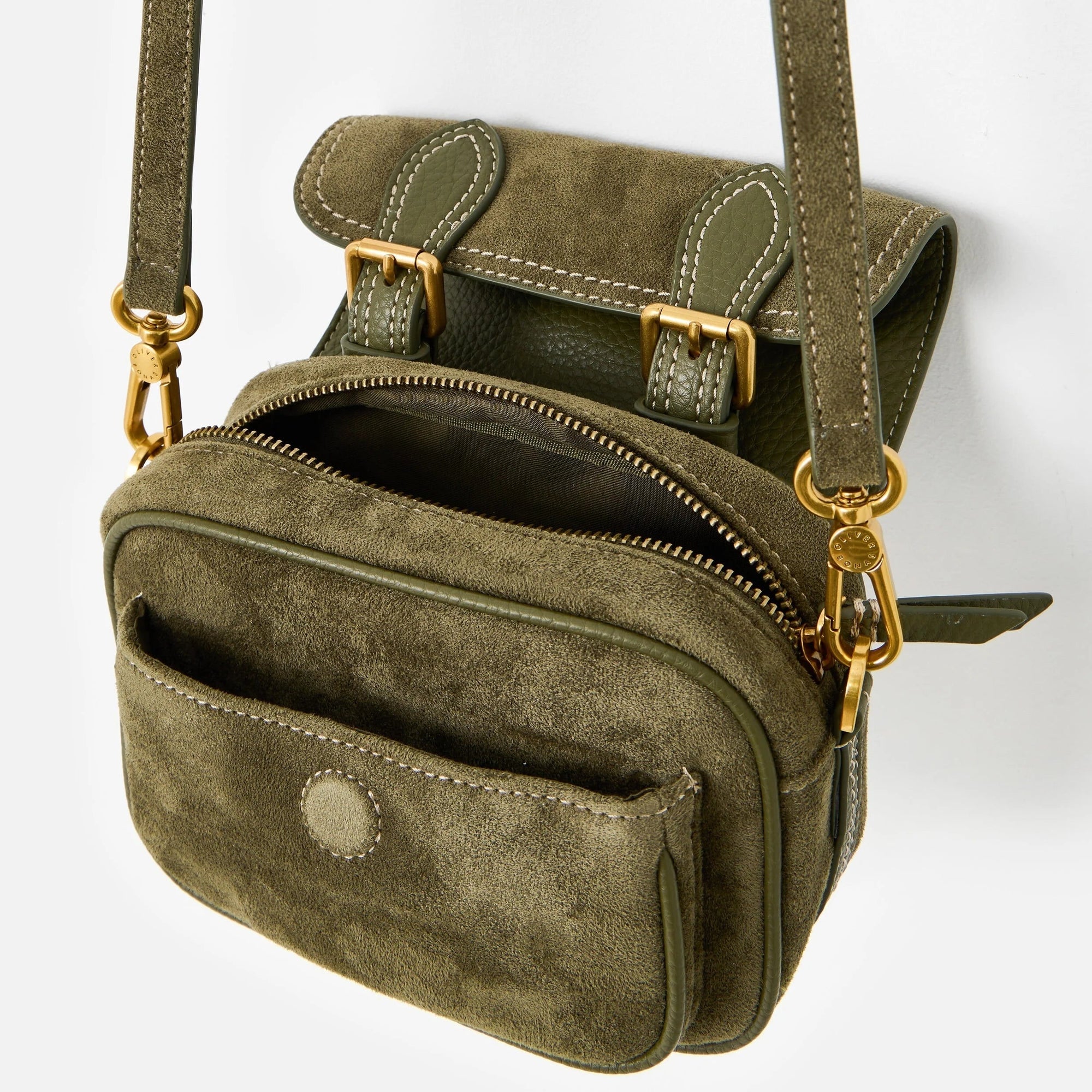 An olive green crossbody bag made of suede and leather, featuring gold-tone hardware, a front zippered pocket, and a top flap with buckle details, shown against a plain white background.