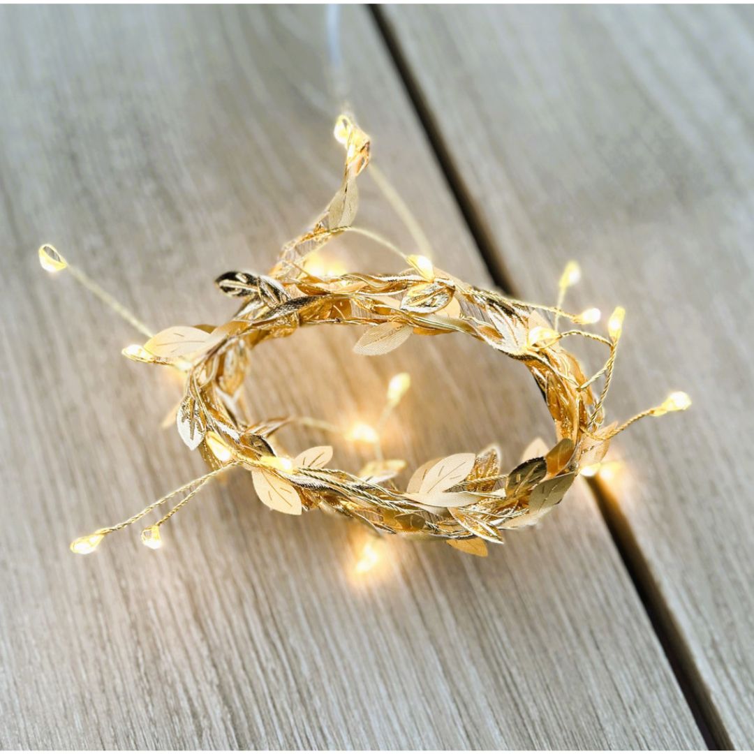 Decorative gold wreath with string lights on a wooden surface