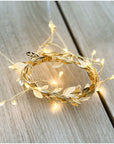 Decorative gold wreath with string lights on a wooden surface