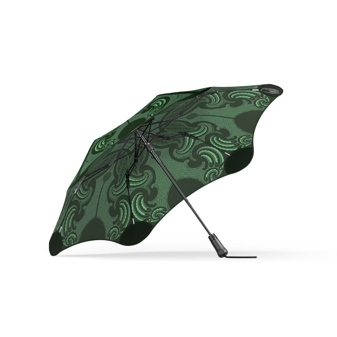 A closed compact umbrella with a dark green and black wavy pattern, shown open against a plain white background.