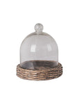 Glass cloche on a wicker stand against a light gray background