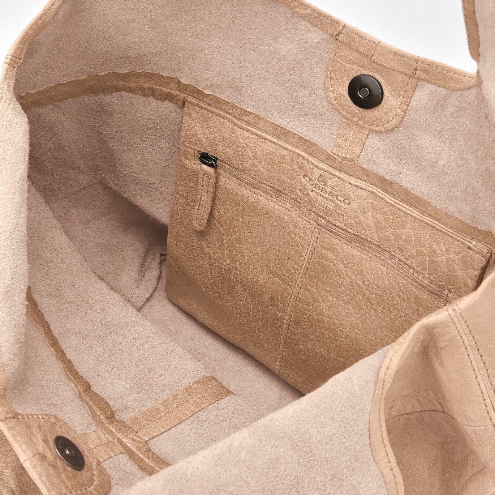 Close-up of a beige bag with visible branding on a light background