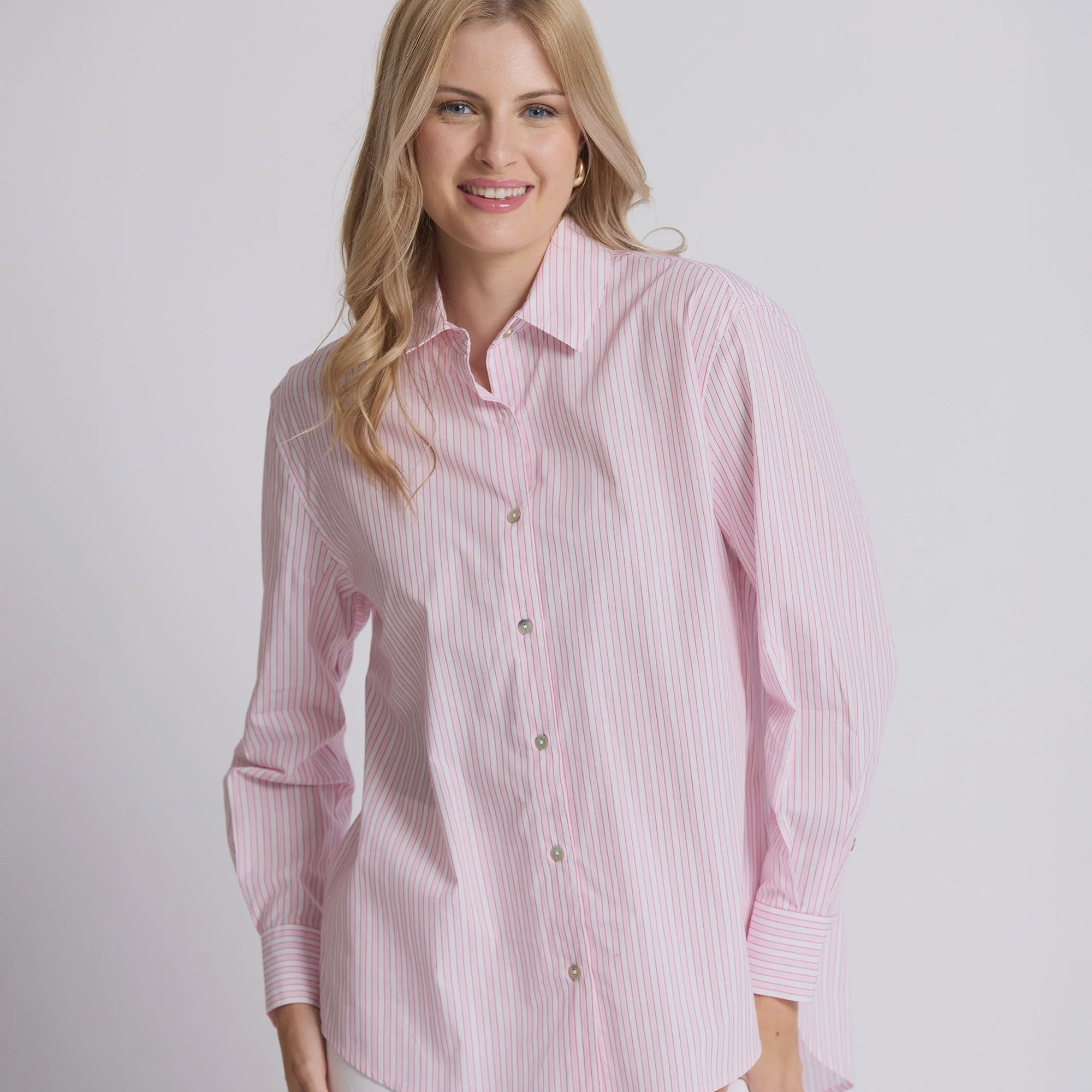 Woman wearing a pink striped shirt against a plain background