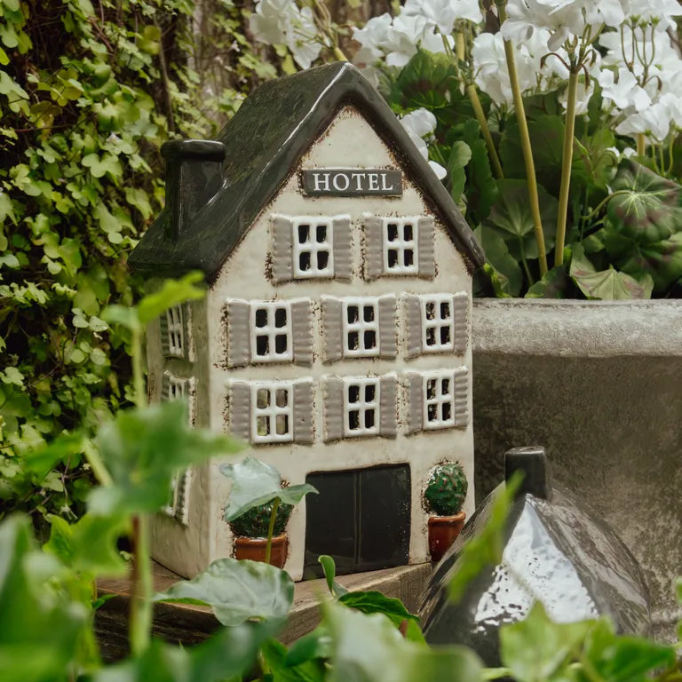 Miniature model of a hotel surrounded by greenery and white flowers