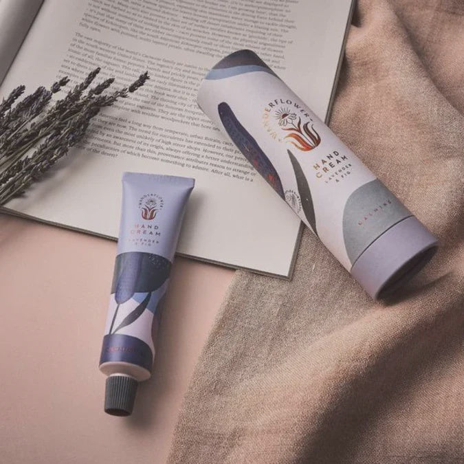 Two tubes of hand cream on a textured surface with a book and lavender.